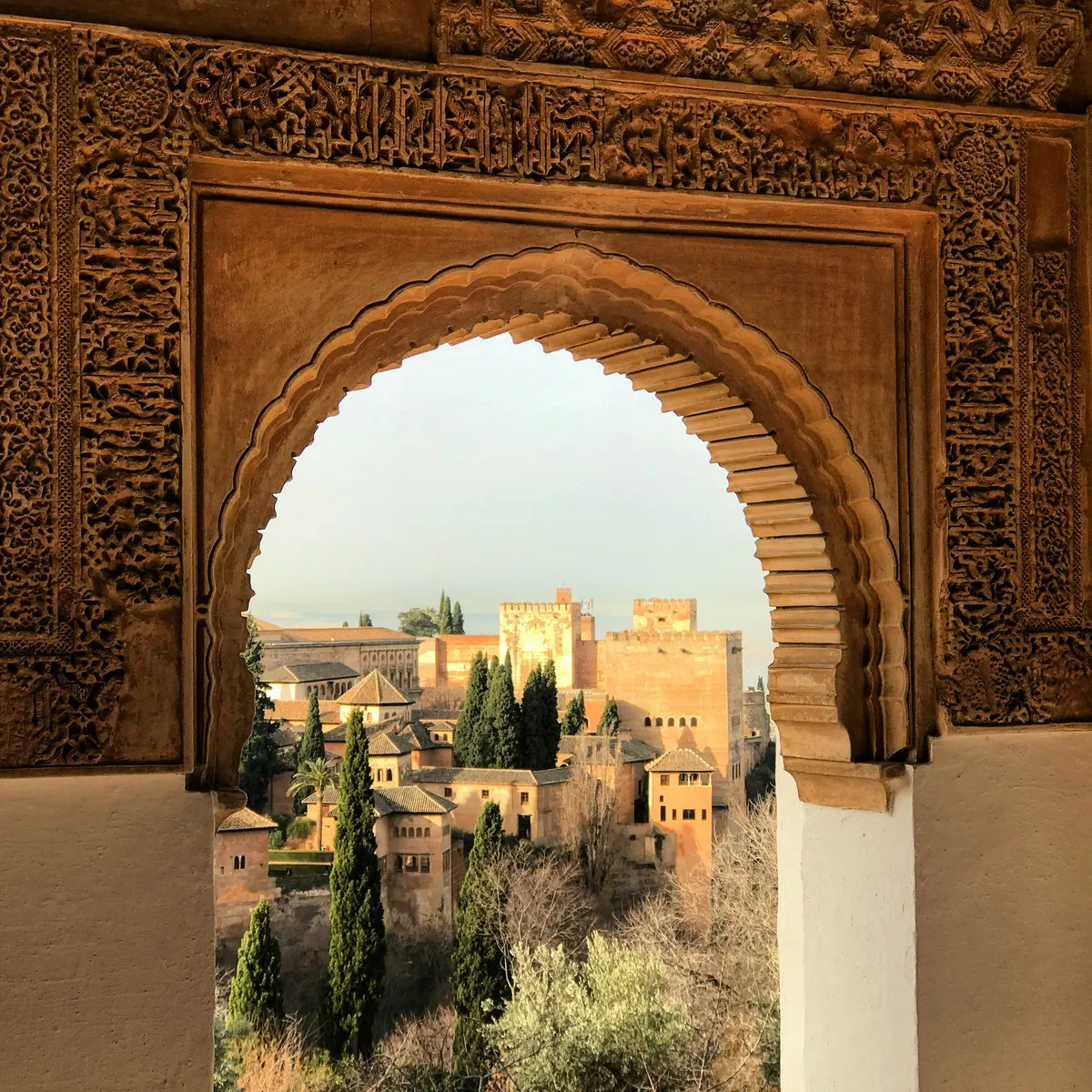 Vista de la Alhambra de Granada a través de un arco decorado